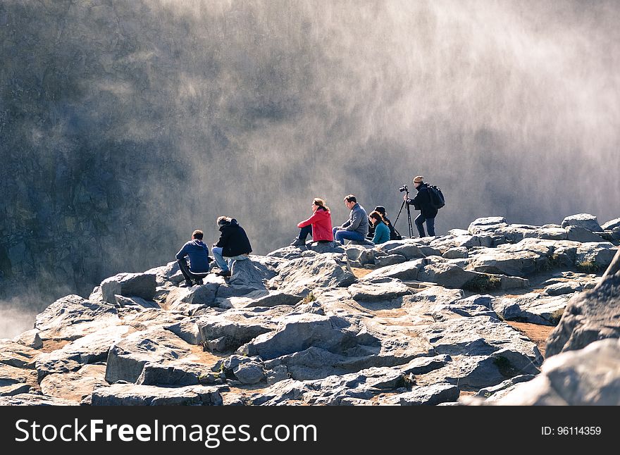 A group of people on a rocky mountain ledge. A group of people on a rocky mountain ledge.