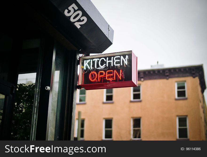 A neon kitchen open sign at the restaurant entrance.