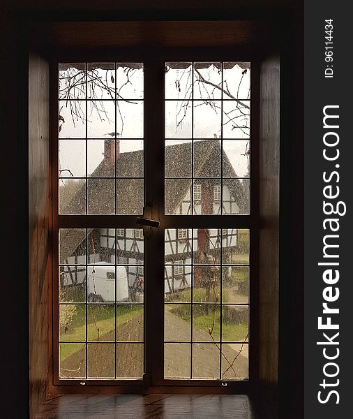 A classic window panel with a view of an old half-timbered house.