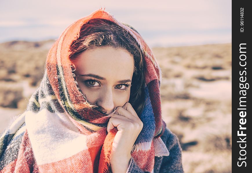A portrait of a young woman with a plaid scarf over her face. A portrait of a young woman with a plaid scarf over her face.