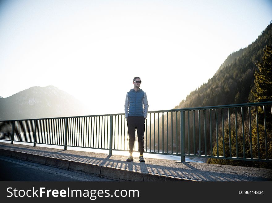 A casual young man standing on a bridge at sunset. A casual young man standing on a bridge at sunset.