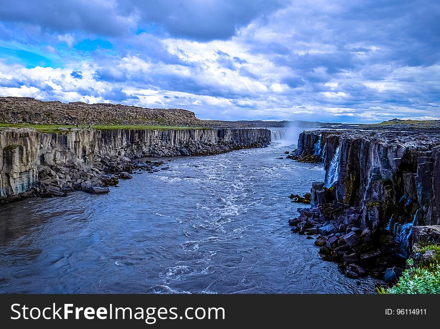 A river flowing through a canyon and waterfall in the distance. A river flowing through a canyon and waterfall in the distance.