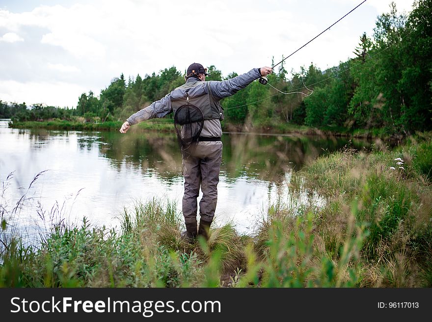 Man in Brown Pants Casting Fishing Rod Into Lake