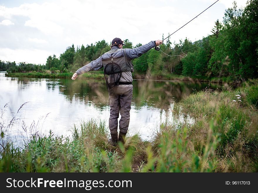 Man In Brown Pants Casting Fishing Rod Into Lake