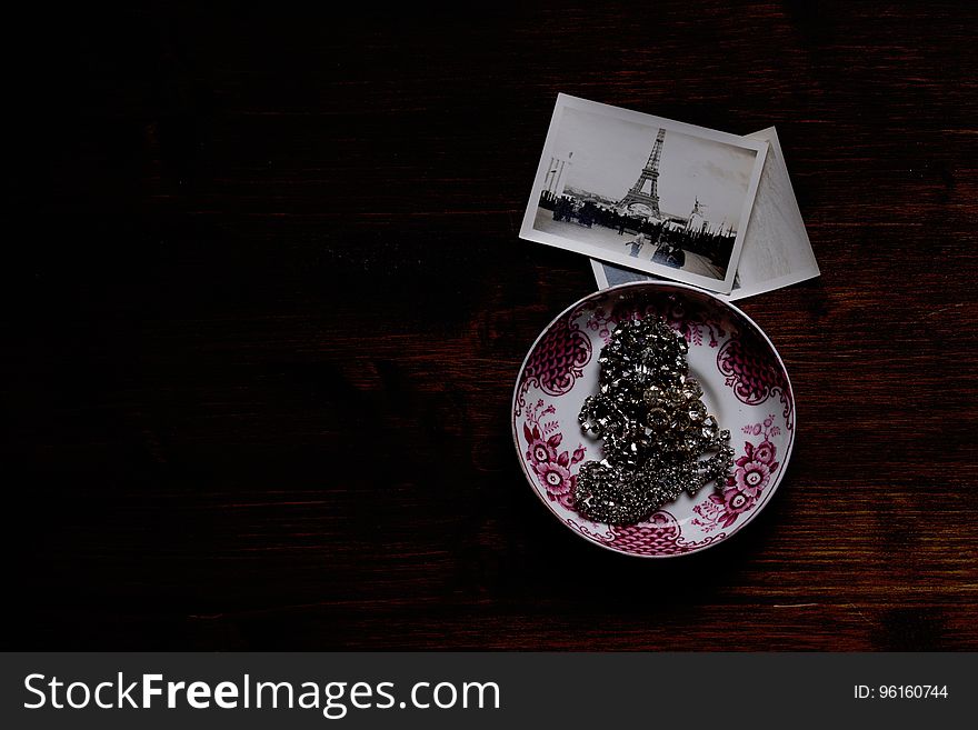 Silver Chain Accessory on White and Purple Ceramic Plate Near Grayscale Eiffel Tower Picture