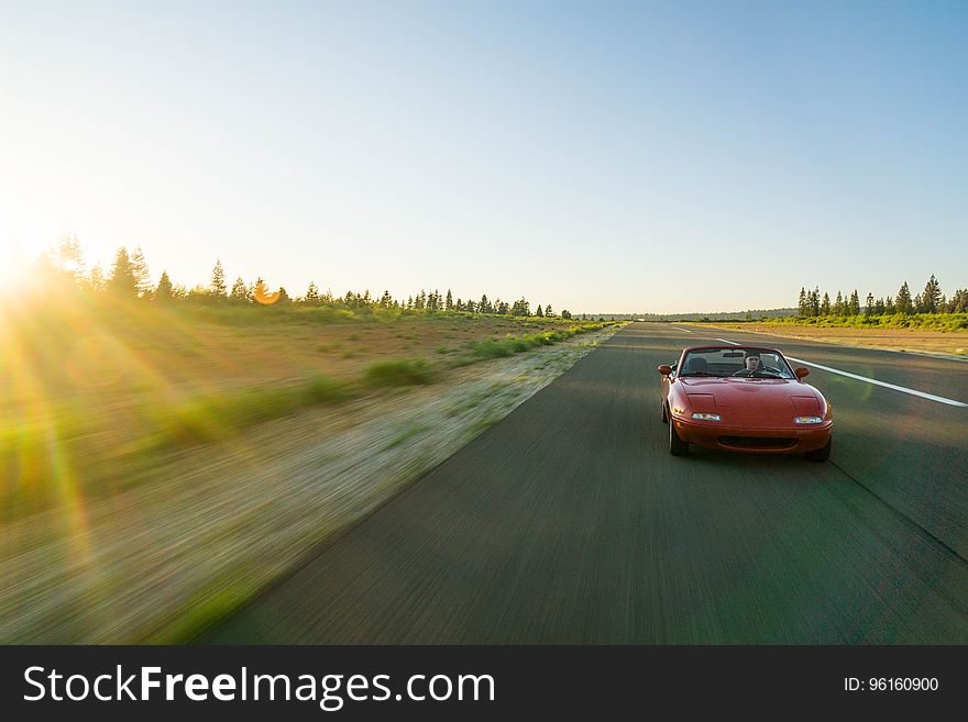 Red Sports Car Running on the Road Under Blue Sky during Daytime
