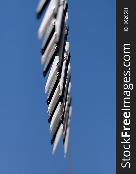 A row of black and white clothes pegs on a line with a blue sky background