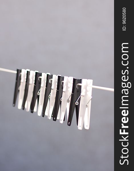 A row of black and white clothes pegs on a line with a blue sky background