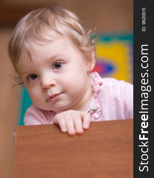 Little girl looking at you out of a table - shallow DOF