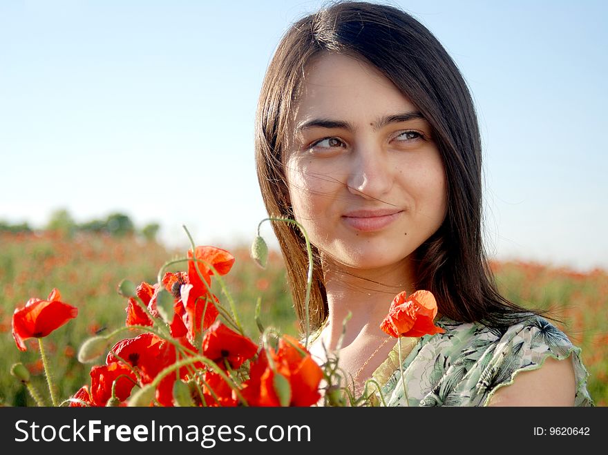 A beautiful girl standing on a field filled with red poppies. A beautiful girl standing on a field filled with red poppies