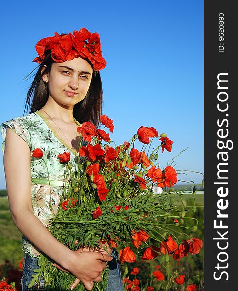 A beautiful girl standing on a field filled with red poppies. A beautiful girl standing on a field filled with red poppies