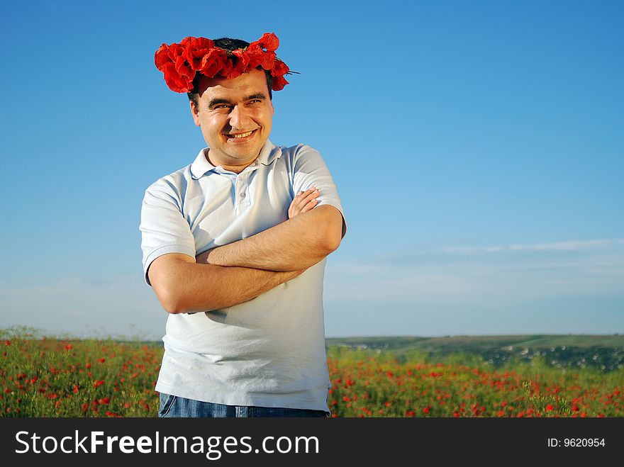 A man standing on a field filled with red poppies and smile. A man standing on a field filled with red poppies and smile