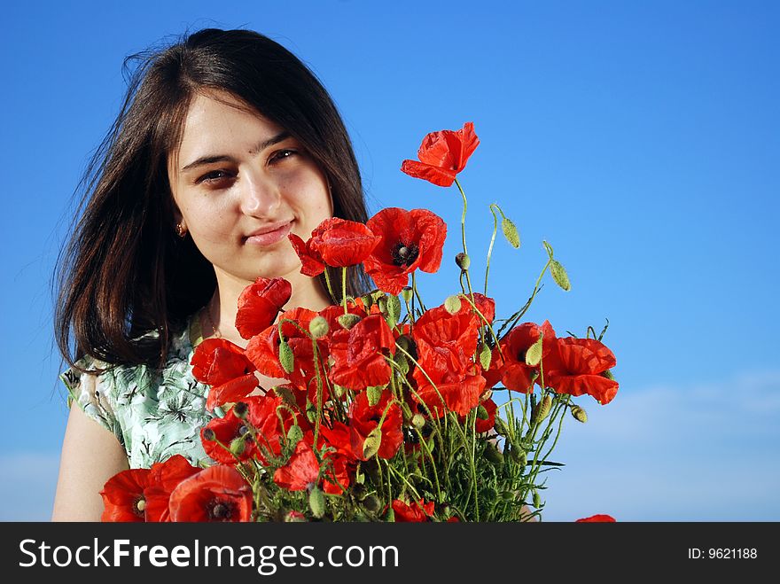 A beautiful girl standing on a field filled with red poppies. A beautiful girl standing on a field filled with red poppies