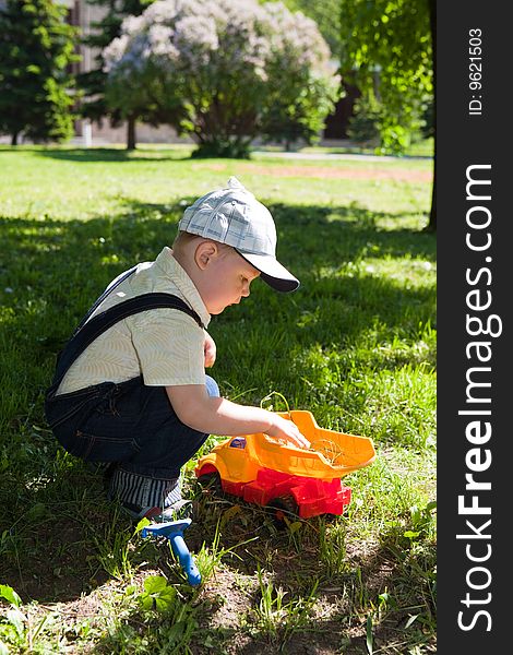 Boy plays the toy car on a green grass