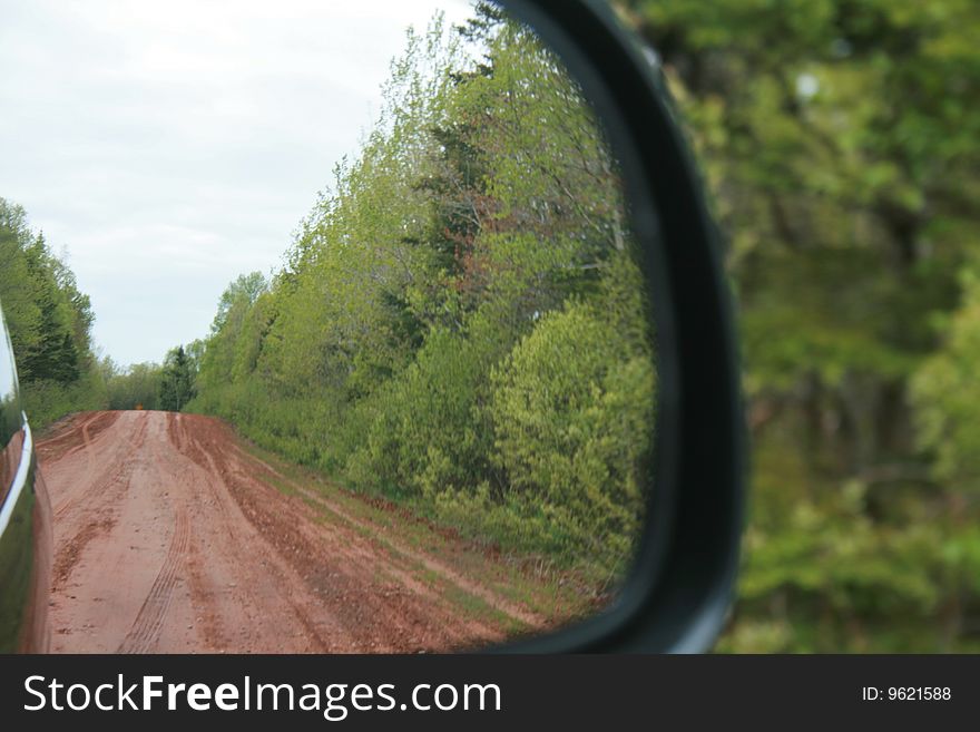 The view of a dirt road out the rearview mirror. The view of a dirt road out the rearview mirror