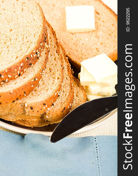 Multi-grain wheat  Bread stacked on blue plate with butter and knife. Multi-grain wheat  Bread stacked on blue plate with butter and knife