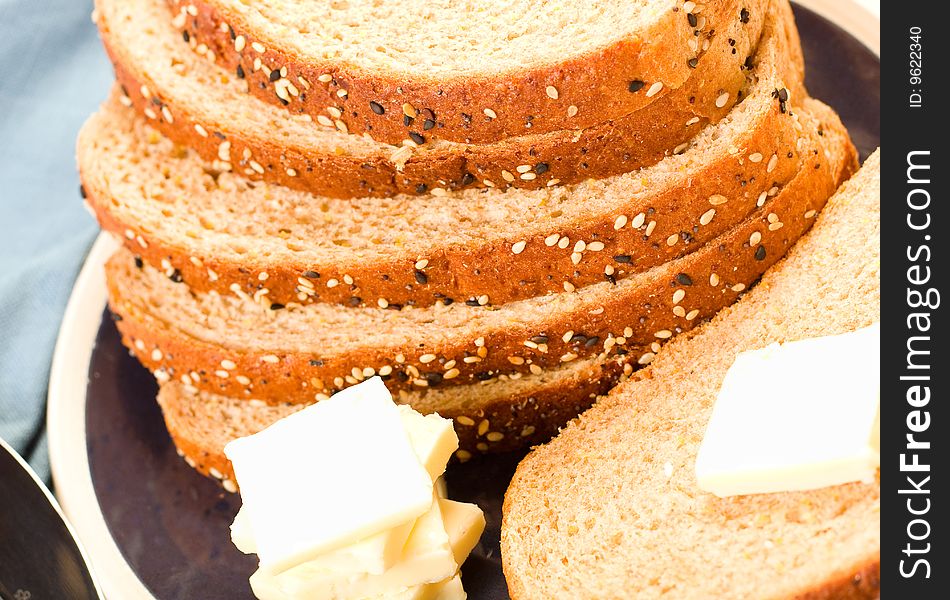 Multi-grain wheat  Bread stacked on blue plate with butter and knife. Multi-grain wheat  Bread stacked on blue plate with butter and knife