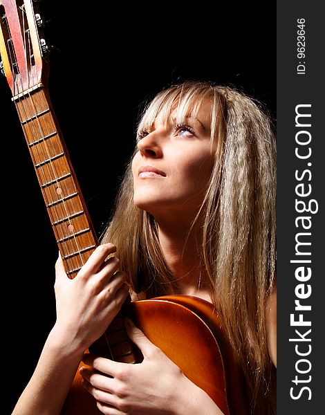 Nice girl with a guitar on a black background