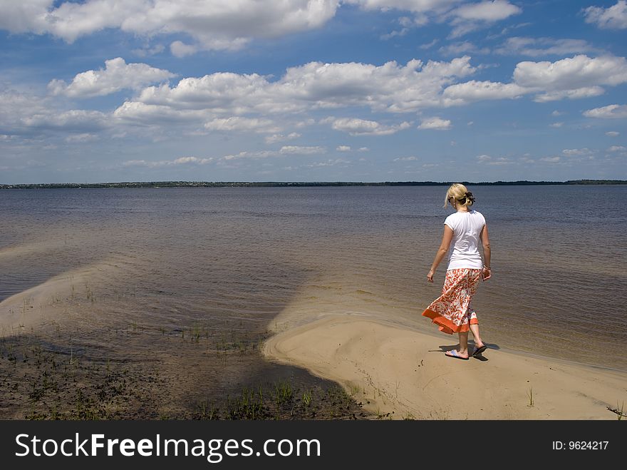 A girl posing with a lake and blue sky in the background. A girl posing with a lake and blue sky in the background.