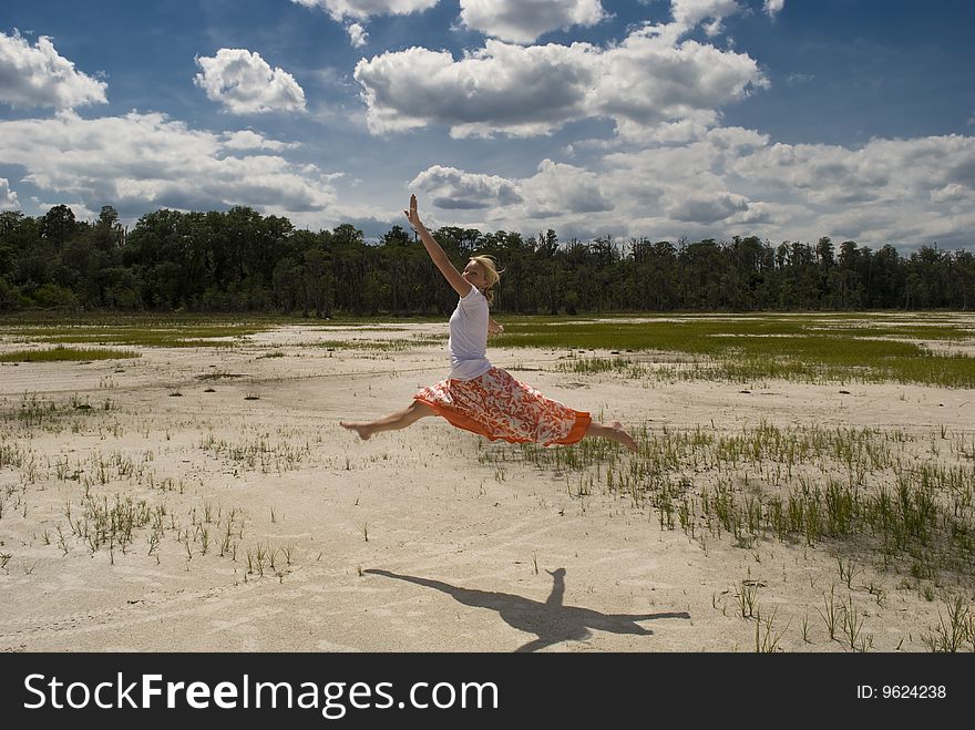 A woman leaping through the air next on a sandy beach with a beautiful landscape in the background. A woman leaping through the air next on a sandy beach with a beautiful landscape in the background.