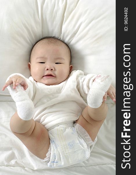 A beautiful smiling baby on white sheets. A beautiful smiling baby on white sheets