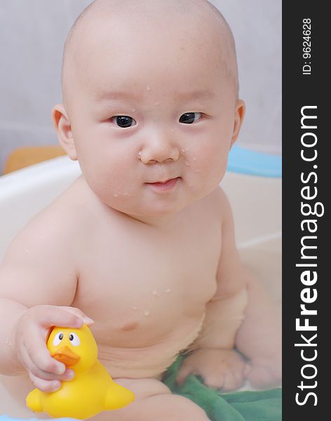 Asian baby boy holding  a yellow plastic duck in bath. Asian baby boy holding  a yellow plastic duck in bath