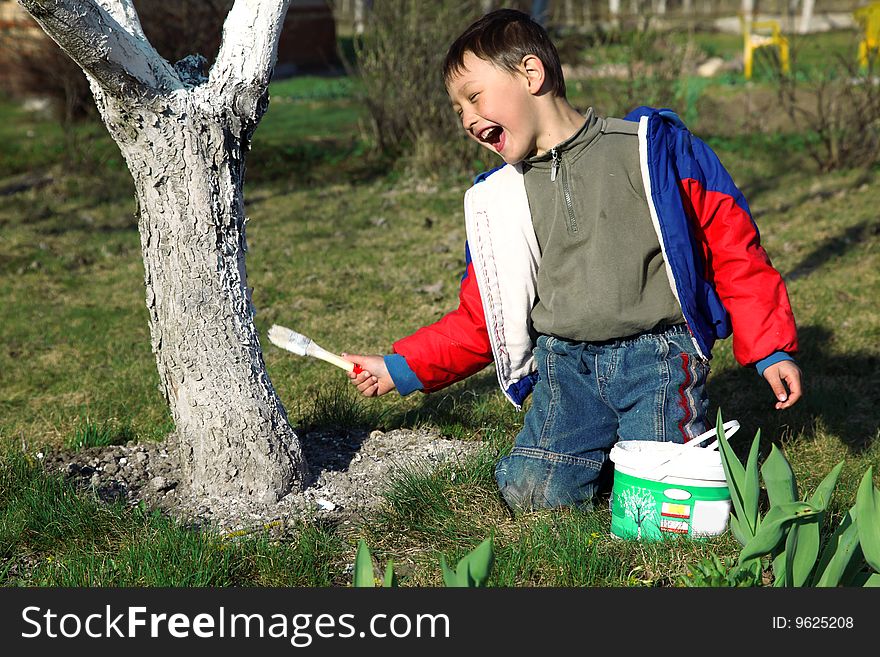 Boy painting apple tree outdoors