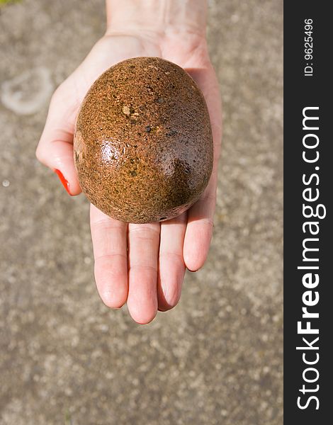 Single hand holding a stone out stretched with a stone background. Single hand holding a stone out stretched with a stone background