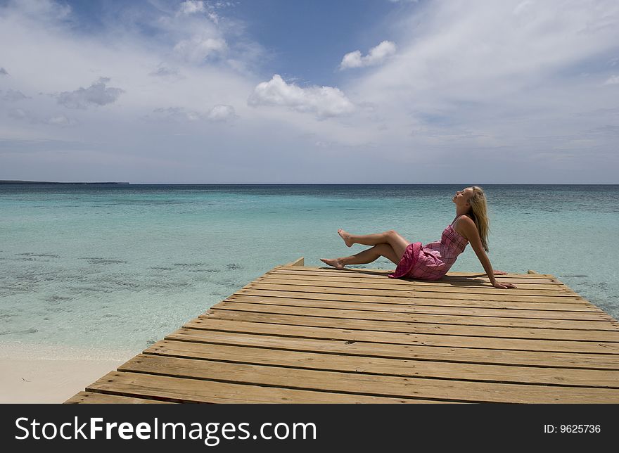 Picture of a woman enjoying the sun on a dock overlooking the Caribbean. Shot at Bahia de Las Aguilas in the Dominican Republic. Picture of a woman enjoying the sun on a dock overlooking the Caribbean. Shot at Bahia de Las Aguilas in the Dominican Republic.