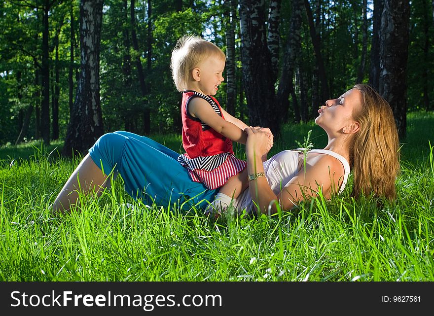 Young mother playing with  daughter on grass