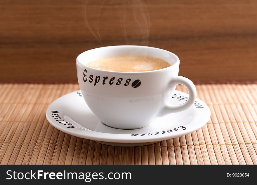 A cup of fresh coffee in front of a wooden background