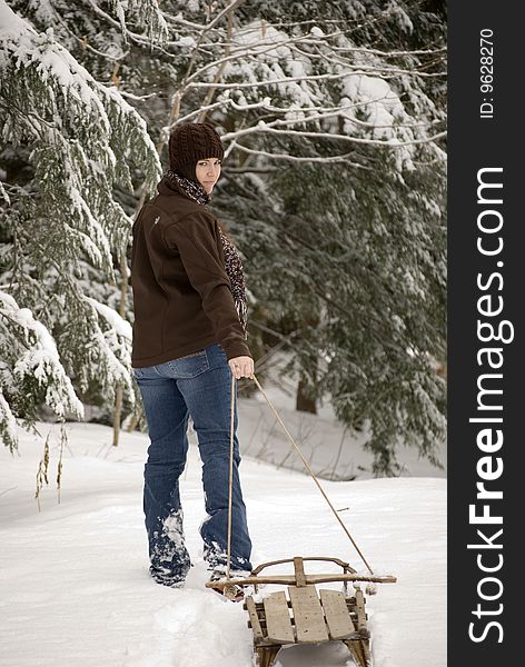 Pretty young woman pulling sled through snow. Pretty young woman pulling sled through snow