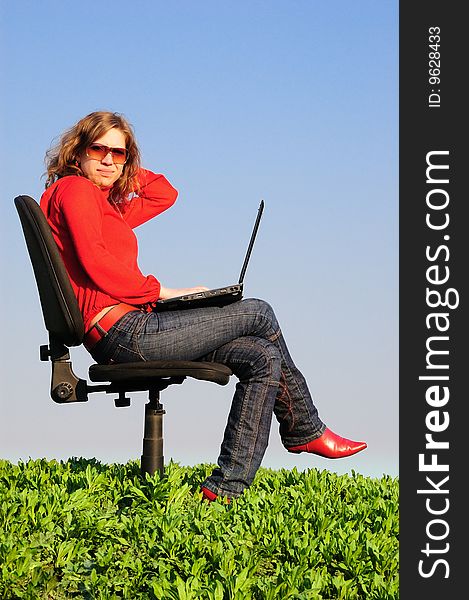 The beautiful girl in armchair with the laptop. Spring. Field. The beautiful girl in armchair with the laptop. Spring. Field