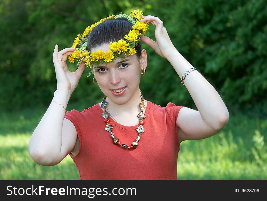 The young woman with a wreath from dandelions on a head. The young woman with a wreath from dandelions on a head