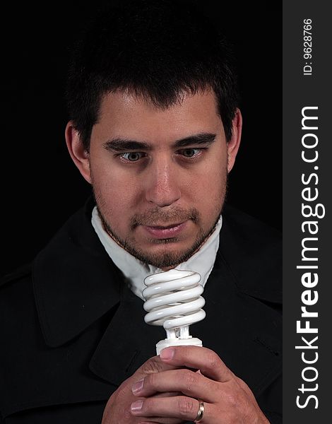 Male portrait staring at new light bulb isolated on black background