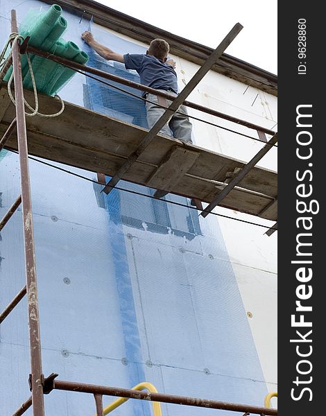 Builder bolts stucco net on wall