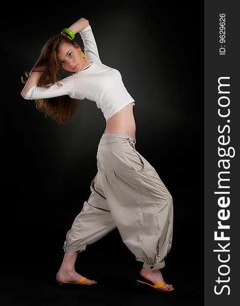 Dancing pose of young girl against a black background with aureole. Dancing pose of young girl against a black background with aureole