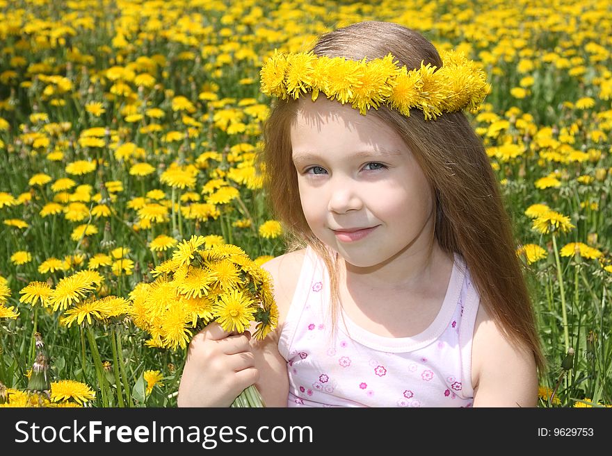 The little girl on a meadow with a bouquet of dandelions