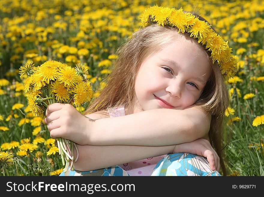 The little girl on a meadow with a bouquet of dandelions
