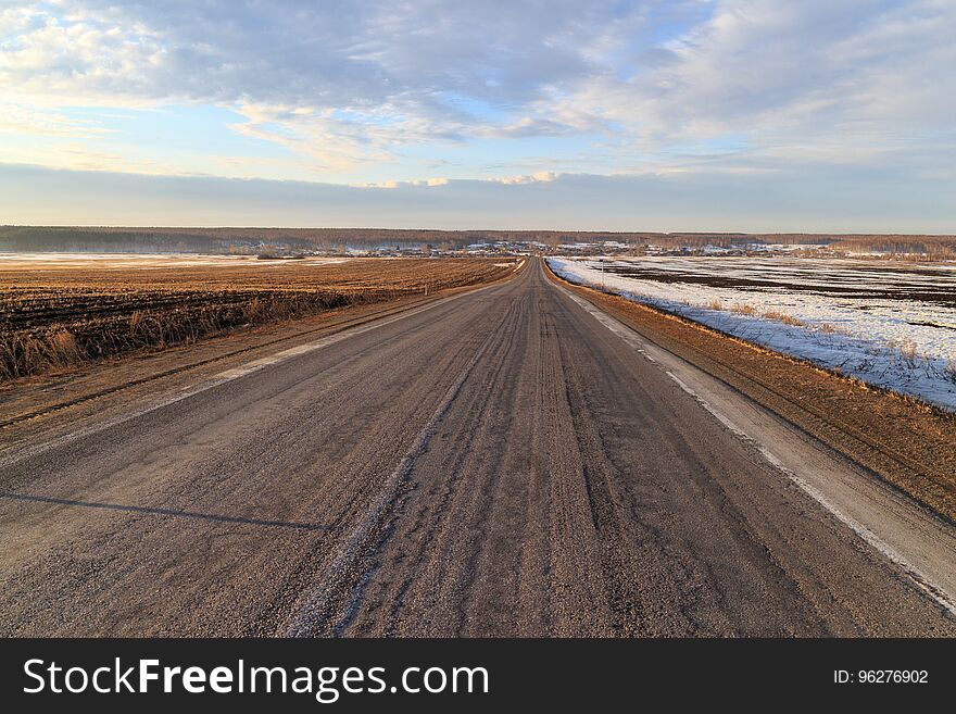 Winter road leading through a field of snow, broken asphalt, Russia