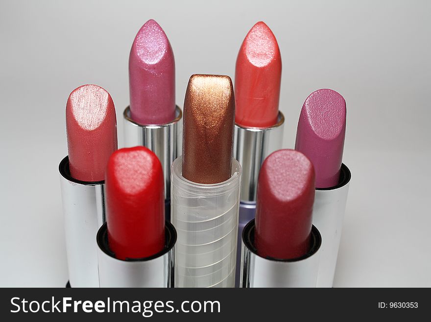 Seven lipsticks in various colors in a white background.