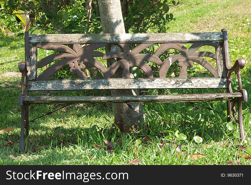 Photo of a weathered park bench under a tree. Photo of a weathered park bench under a tree