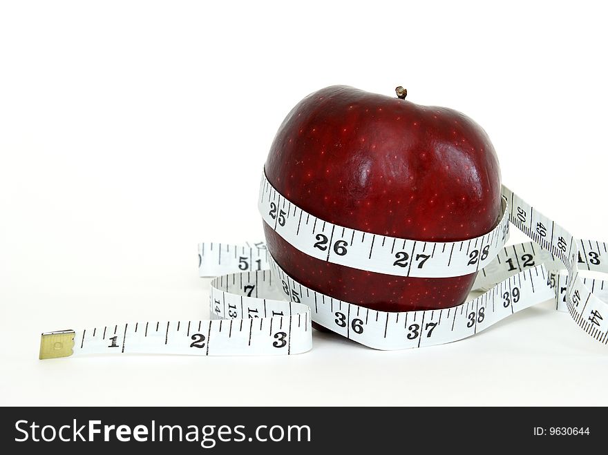 A red apple with a measuring tape wrapped around it for the concept of healthy eating. A red apple with a measuring tape wrapped around it for the concept of healthy eating.