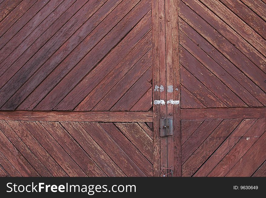 The closed old wooden gate with the cracked brown paint