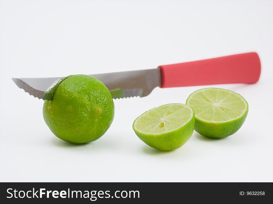 Kitchen knife with red handel cutting green limes in half. Kitchen knife with red handel cutting green limes in half