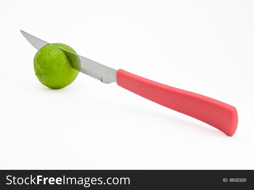 Kitchen knife with red handel cuts a fresh lime in half. Kitchen knife with red handel cuts a fresh lime in half