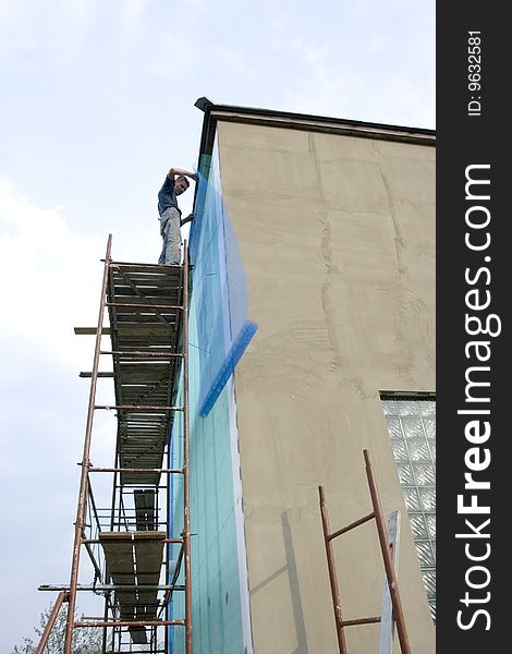 Builder bolts stucco net on wall