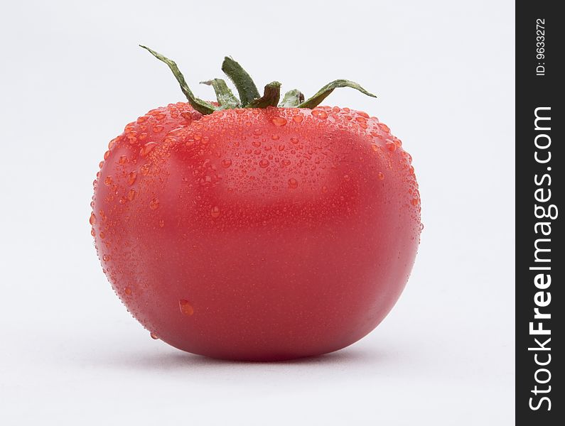 The ripe and juicy red tomato with drops.