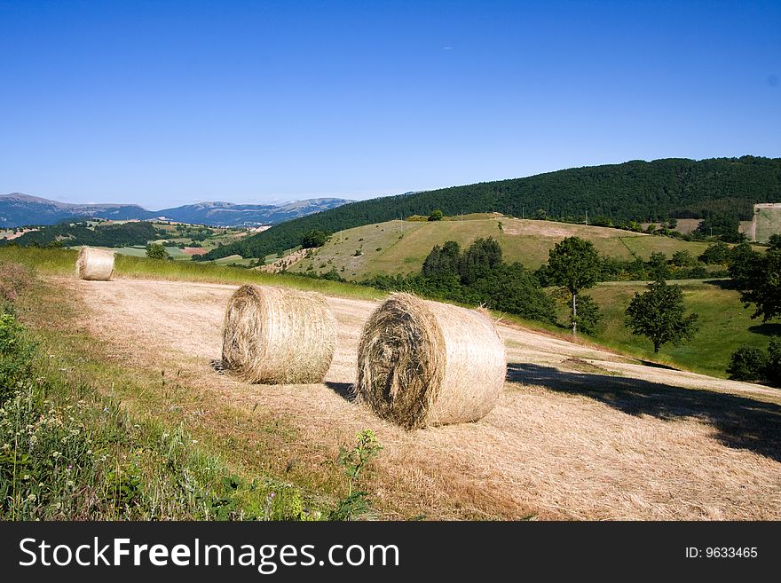 Photo of the italian country with three hay bales in the summer