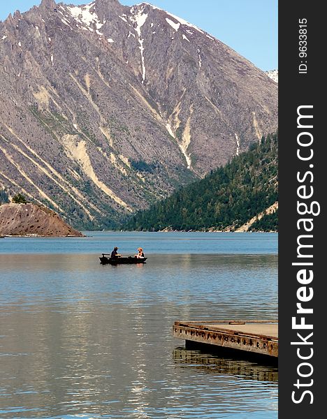 Fishing boat underneath the mountains in the clear waters of coldwater lake. Fishing boat underneath the mountains in the clear waters of coldwater lake